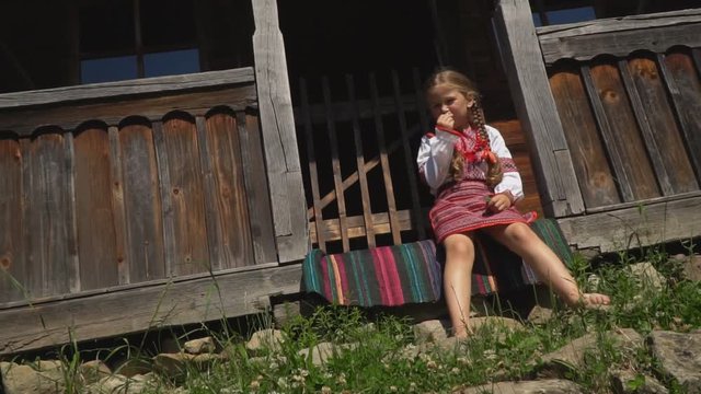 little girl is sitting on the porch of the house