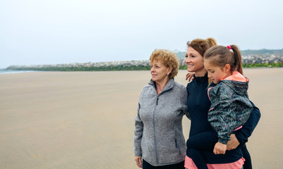 Three generations female looking at sea on the beach in autumn