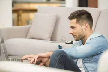 Young man in living-room using laptop computer