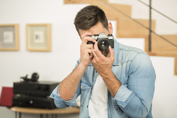 Man at home using vintage reflex camera