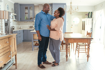 Affectionate African couple smiliing and standing together in their kitchen