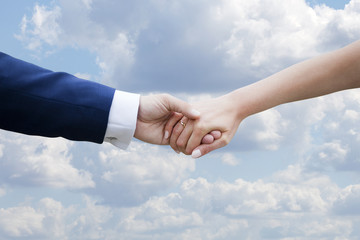 Wedding couple holding hands on blue sky with clouds