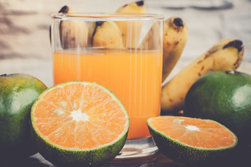 Fototapeta na wymiar a glass of freshly squeezed orange juice and fresh tropical fruits