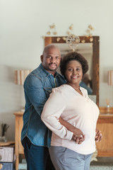 Smiling African couple standing lovingly together in their living room