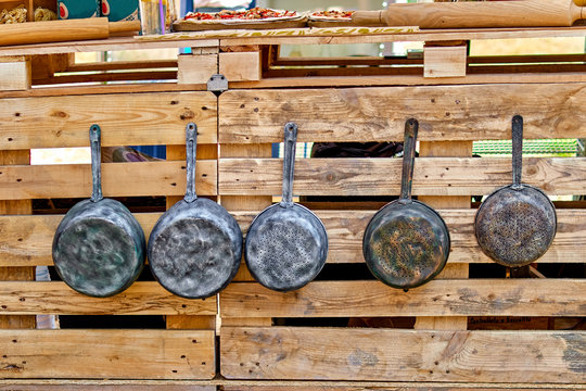 Old iron pots and antique frying pans hang on hooks. old kitchen utensils.