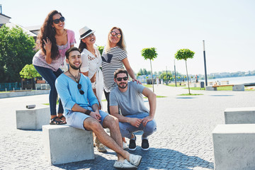 Group of people sitting on a staircase outdoors - Multiracial friends talking and having fun on a meeting outdoors on beach