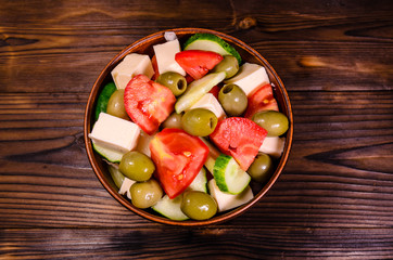 Greek salad in a bowl on wooden table. Top view