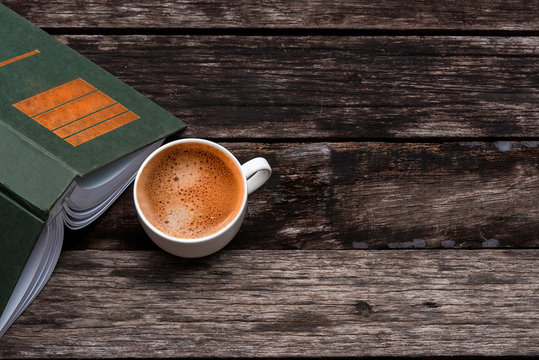 white cup of coffee and a book on wooden table