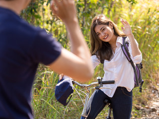 Young asian woman on bicycle say hi/good bye to boyfriend, couple traveling in nature forest during trekking camping at outdoor, freedom lifestyle and relaxation on holiday concept.