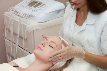Obraz premium Hardware cosmetology. Lovely young woman getting face massage before applying cream mask in a beauty parlour.