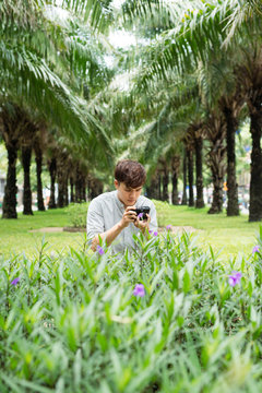 Young asian man photographer taking picturein park