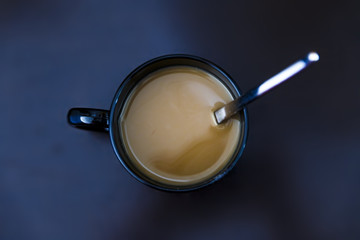 latte coffee in a black mug over dark table