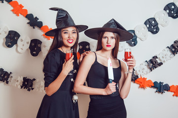 Girls in a witch costume with glasses in hands. Halloween.