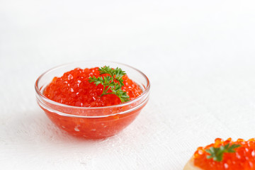 Red salmon caviar in glassware on a white wooden background