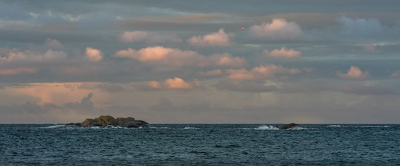 Sunrise with pink sky and clouds over the ocean and archipelago of Faerder National Park, Norway
