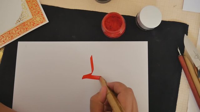 Arabic calligraphy. The calligrapher writes in red ink.