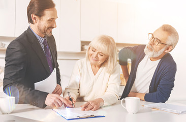 Fototapeta premium Positive couple signing papers with insurance agent