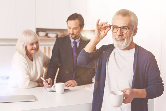 Positive retired man standign in the kitchen