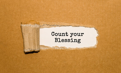 The text Count your Blessing appearing behind torn brown paper