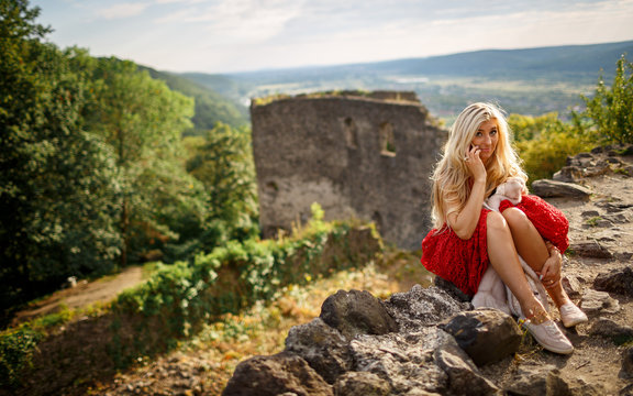 A beautiful blonde speaks by telephone on the background of a medieval castle