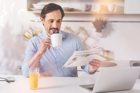 Cheerful adult man reading newspaper