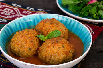 Close up of Koofteh Tabrizi Large Meatballs Stuffed With Dried Fruits, Berries And Nuts In Tomato Turmeric Broth A Traditional Azeri And Iranian Dish Served In Turquoise Bowl