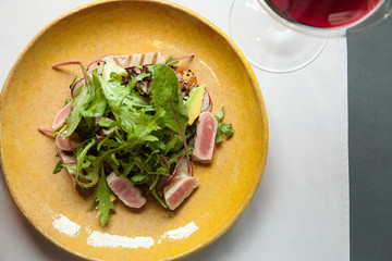 tuna salad with fresh vegetables and a glass of red wine