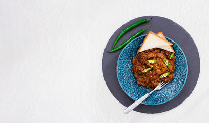 Braised eggplant in tomato and chocolate sauce with green chili peppers. Slate round background. Selective focus. Copy space. Marble background