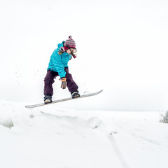 Young woman on the snowboard jumping