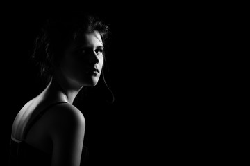 Fototapeta na wymiar beautiful sad young woman on black background with copy space looking at camera, monochrome