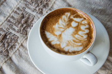 coffee cup with latte art on vintage table background.latte art angle shape pattern on the top of hot coffee for breakfast in coffee shop