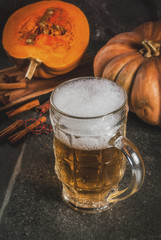 Frothy spicy pumpkin Ale or beer in glass mug, on black background, copy space