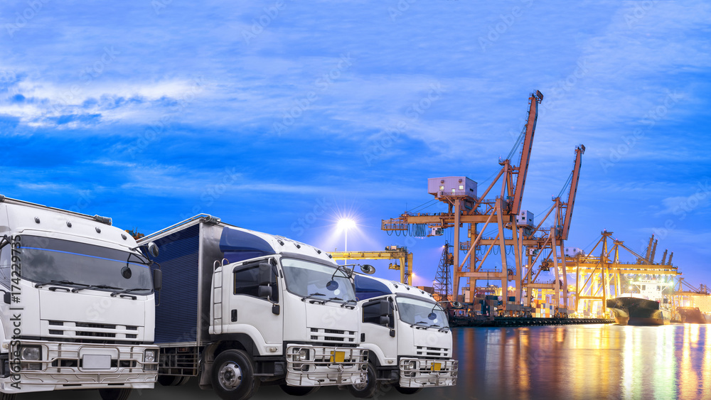 Wall mural Shipping Yard Import and Export Delivery Order Schedule Concept, Truck foreground and shipping port background in the early morning