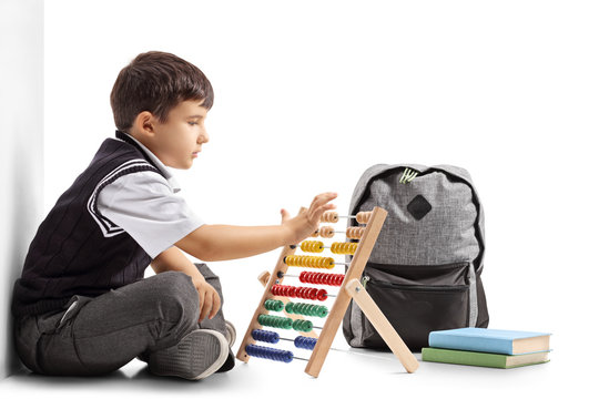 Schoolboy seated on the floor using an abacus