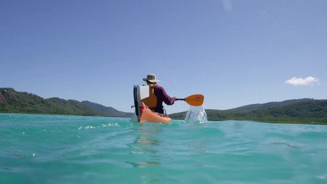 A slow motion wide shot of a man kayaking that already crossed the camera shot under a sunny day.