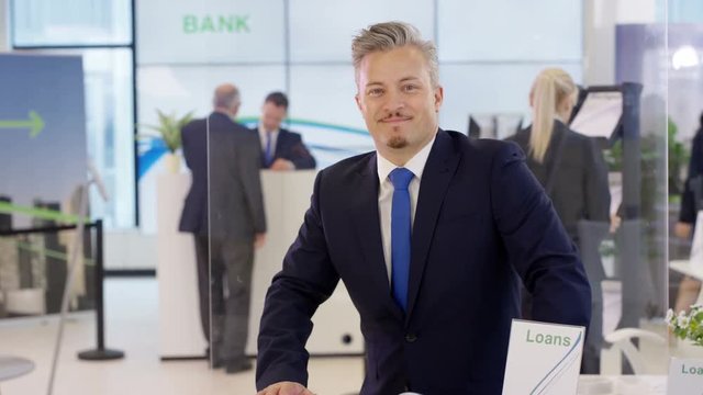  Portrait of friendly smiling financial adviser at customer help desk in bank
