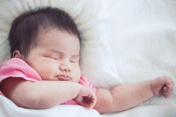 Asian newborn baby girl sleeping on white bed