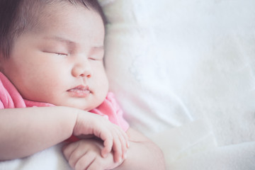 Asian newborn baby girl sleeping on white bed