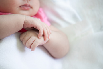 Fototapeta na wymiar Newborn baby girl hands holding while she sleeping on white blanket