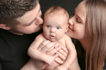 Happy young family holding newborn baby, closeup
