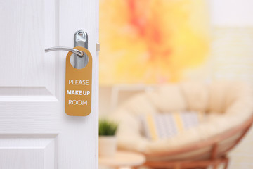Fototapeta premium Open door with sign PLEASE MAKE UP ROOM on handle at hotel