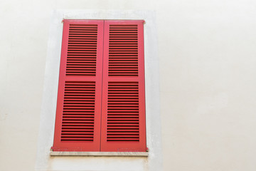 Roter Fensterladen in weißer Fassade