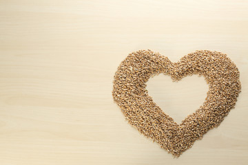 Heart made of cereal grains on wooden background