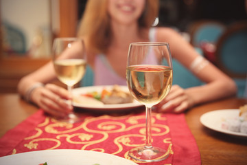 Glass of white wine and blurred young woman in restaurant
