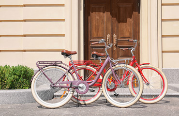 Fototapeta na wymiar Stylish new bicycles near house entrance on city street