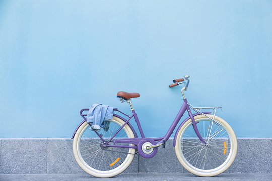 Stylish new bicycle near color wall outdoors
