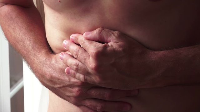 Pain symptoms - abdominal ache. Closeup of man feeling bad and ill, suffering from painful abdomen or stomach. Health care and medicine concepts.
