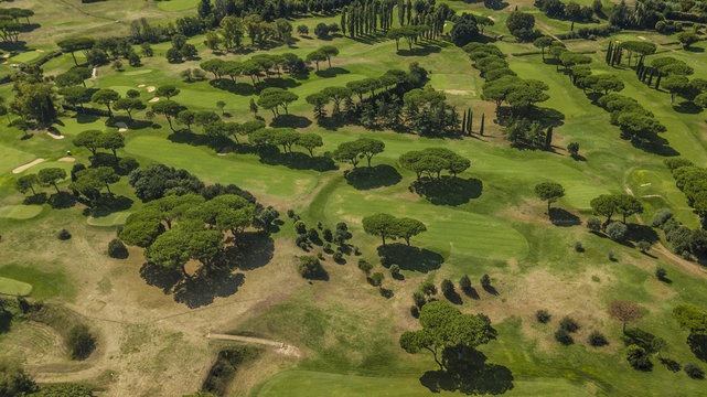 Vista aerea panoramica di un vasto campo da golf presso un circolo sportivo immerso nel verde. Si notano le buche con gli ostacoli per raggiungerle.