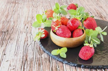 ripe red raspberries and strawberries in wooden bowl, selective focus