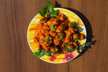 Chicken gizzard stew in plate on wooden table